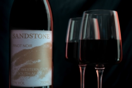 Close-up of Sandstone Pinot Noir with two red wine glasses at Villa Resorts against a dark background