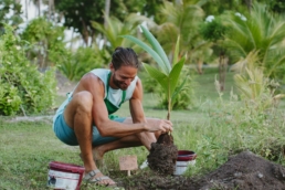 Guest planting a tree outdoors at Villa Park through the Green Fingers sustainability experience