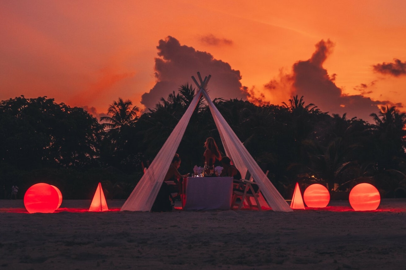 Private candlelit beach dining setup at Villa Nautica in the Maldives during sunset