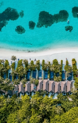 Aerial view of the beach at Villa Nautica, with turquoise lagoon, white sand shoreline and beachfront villas lined with palm trees