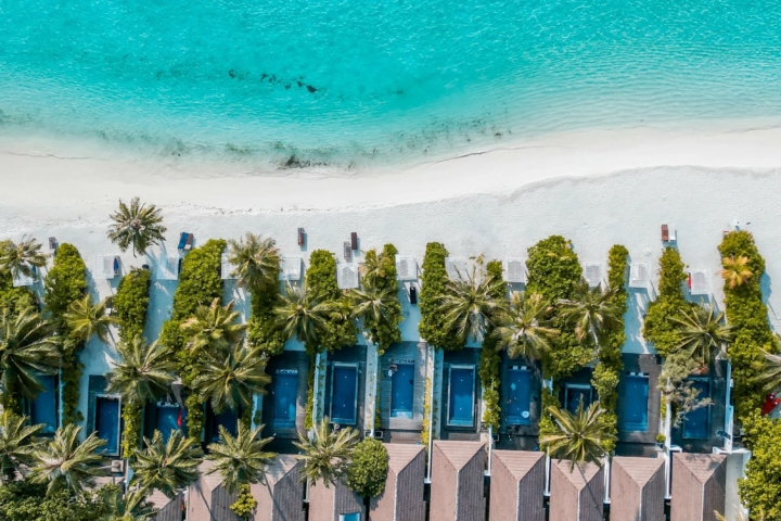 Aerial view of the beach at Villa Nautica, with turquoise lagoon, white sand shoreline and beachfront villas lined with palm trees