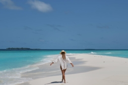 Guest walking along a white sandbank with turquoise lagoon at Royal Island Maldives in Baa Atoll