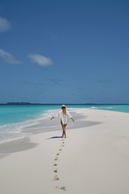 Guest walking along a white sandbank with turquoise lagoon at Royal Island Maldives in Baa Atoll