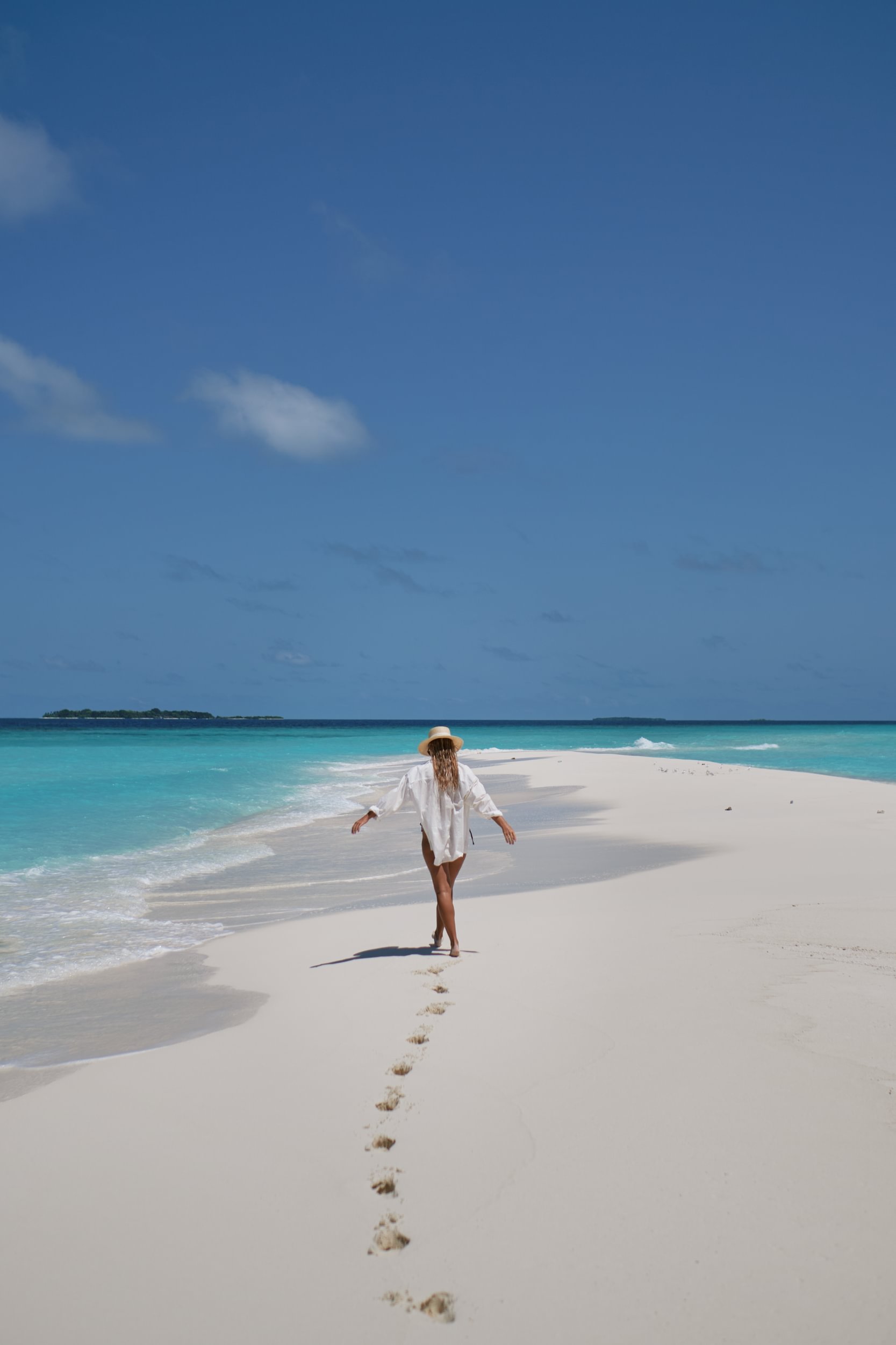 Guest walking along a white sandbank with turquoise lagoon at Royal Island Maldives in Baa Atoll