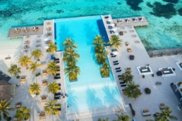 Aerial view of Villa Nautica’s infinity pool overlooking the turquoise lagoon in North Malé Atoll.