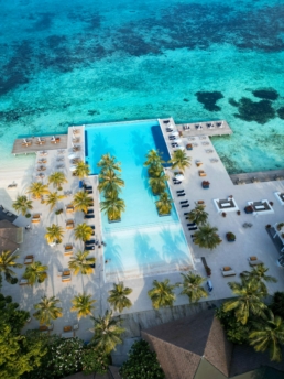 Aerial view of Villa Nautica’s infinity pool overlooking the turquoise lagoon in North Malé Atoll.