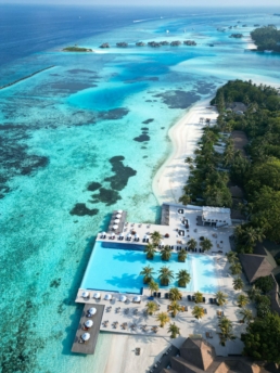 Aerial view of Villa Nautica’s infinity pool overlooking the turquoise lagoon in North Malé Atoll.